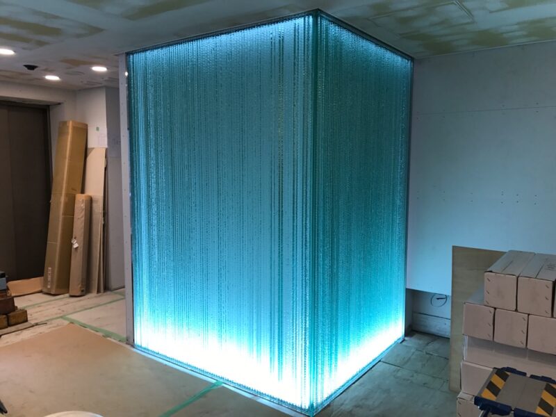 バックライトで青緑色に光る積層ガラスの壁面